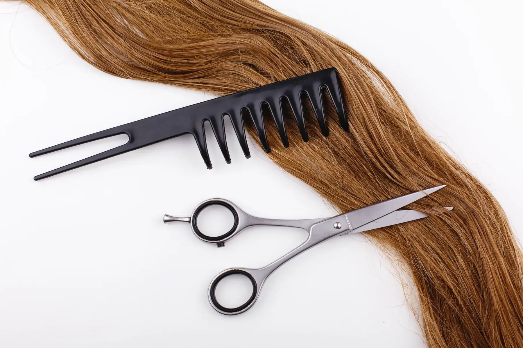 Lengths of glossy hair laid flat beside a comb and shears.